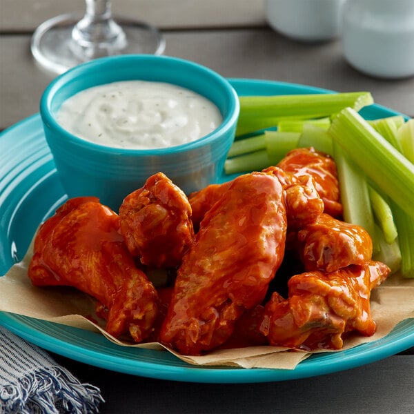 A blue plate of jumbo cut chicken wings with celery sticks and ranch dressing.