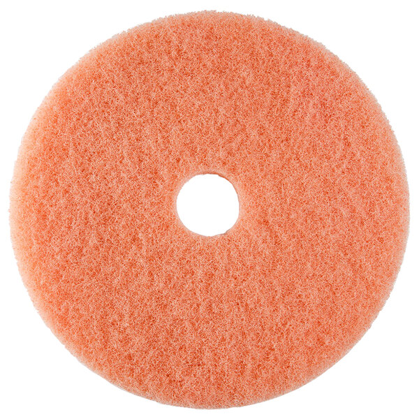 A round orange Scrubble burnishing pad with a hole in the middle.