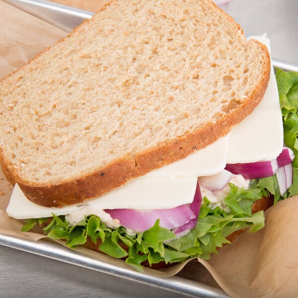 A sandwich with lettuce, onions, and Cooper Sharp White American cheese on a tray.