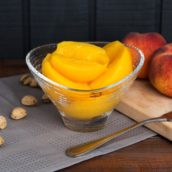 Peach halves in a bowl with a spoon.