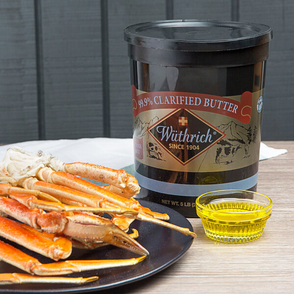 A plate of crab legs and a container of clarified butter on a table.