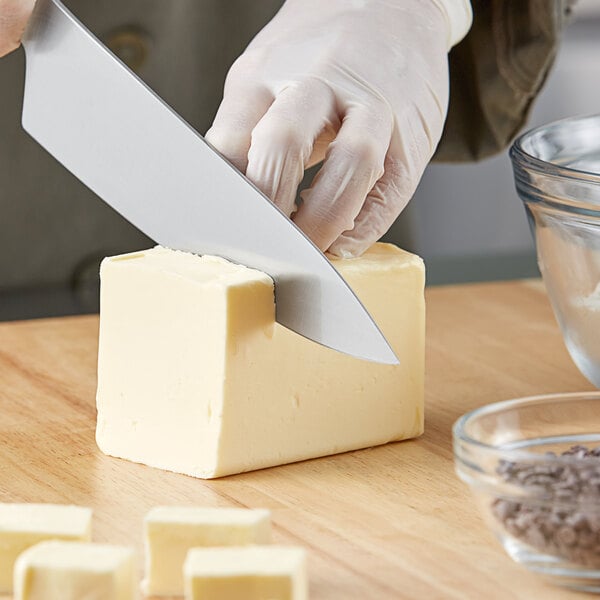 A person cutting a block of Grassland unsalted butter with a knife.