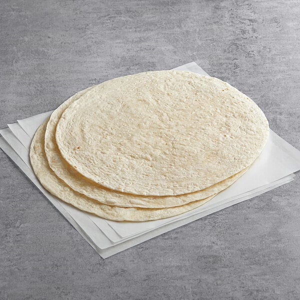 A stack of Father Sam's Bakery flour tortillas on a white surface.