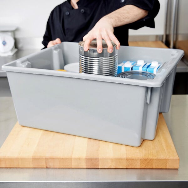 A person holding a can in a Rubbermaid Palletote box.