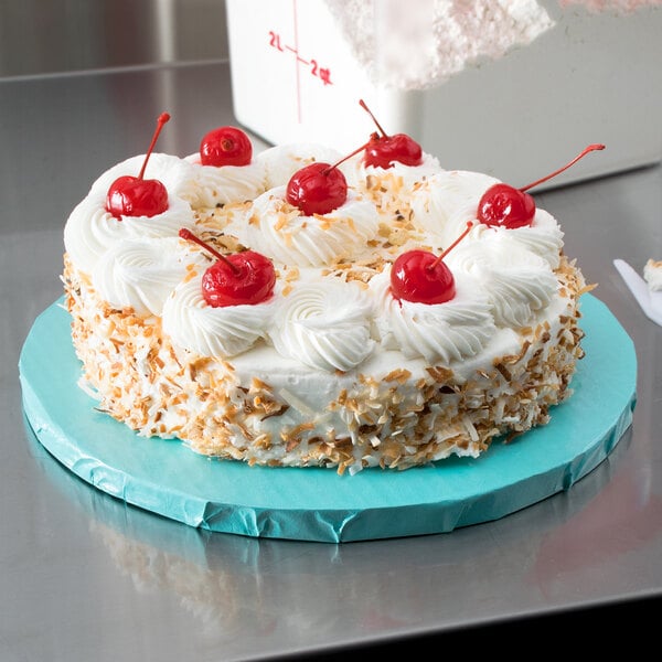 A blue round cake on a blue Enjay cake drum with whipped cream and cherries on top.