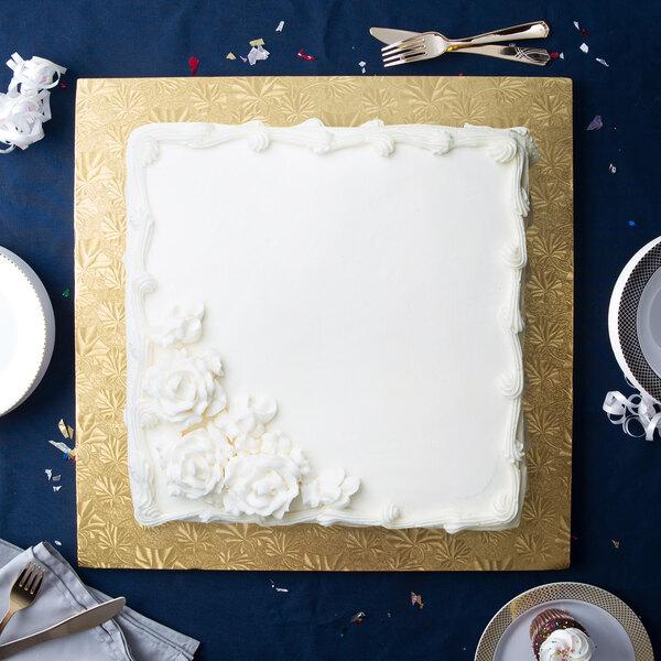 A white cake with white frosting on a gold square cake drum.
