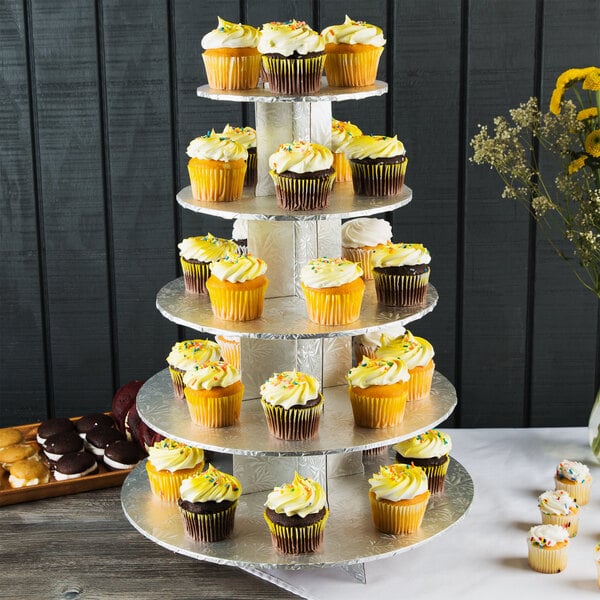 An Enjay silver disposable cupcake stand with a variety of cupcakes on it.