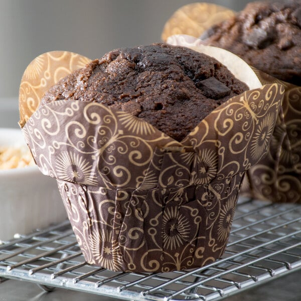 Two muffins in Enjay dark brown lotus baking cup wrappers on a metal rack.