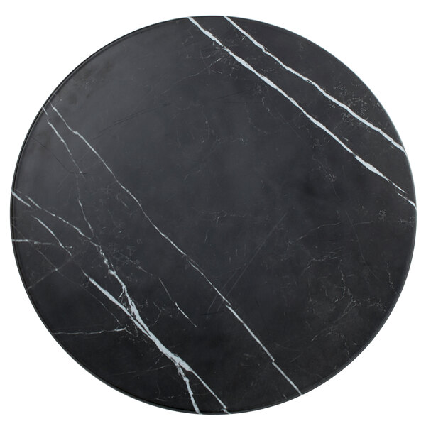 An American Metalcraft faux black marble round melamine serving board on a black and white marble table top.