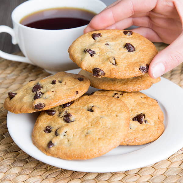 A hand holding a plate of David's Cookies chocolate chip cookies.