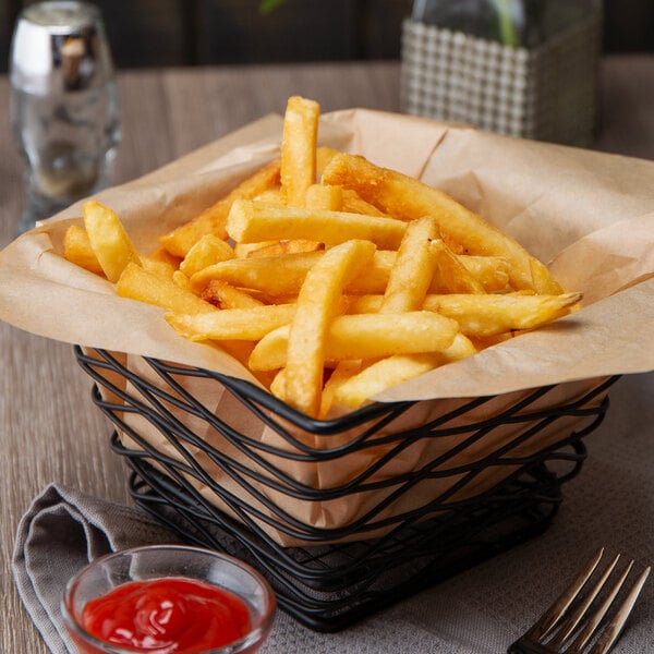 A basket of 5 lb. straight cut French fries with a bowl of ketchup.