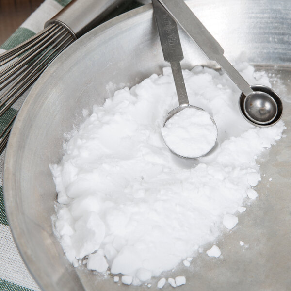 Measuring spoons with white powder in a bowl.