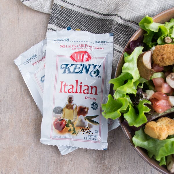 A bowl of salad with a Ken's Foods Lite Italian dressing packet next to it.