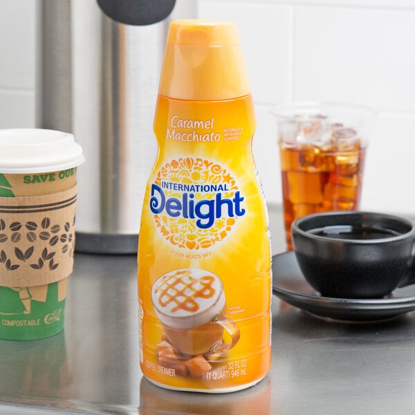 A plastic bottle of International Delight Caramel Macchiato coffee creamer on a counter.