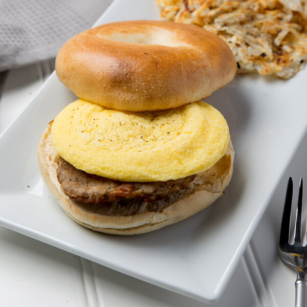 A plate with a bagel sandwich made with a round scrambled egg patty.