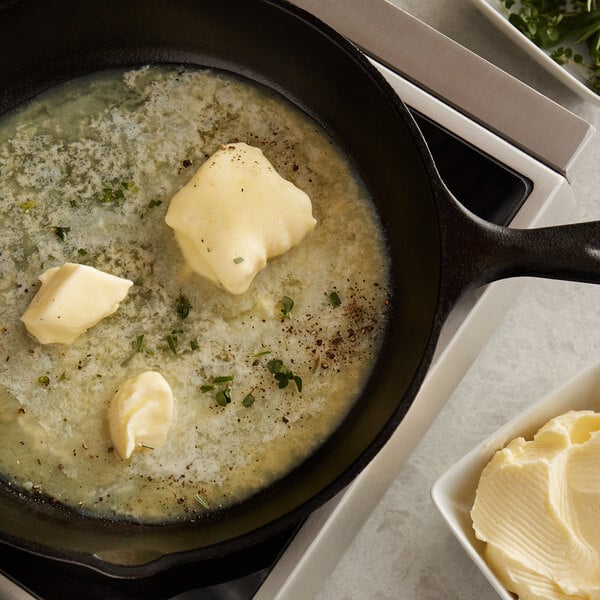 A skillet of food with Grassland butter and herbs cooking.