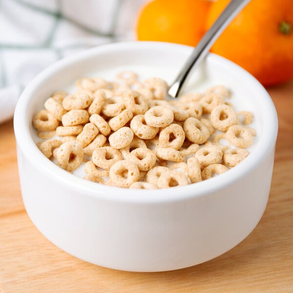 A bowl of Cheerios cereal with a spoon in it.