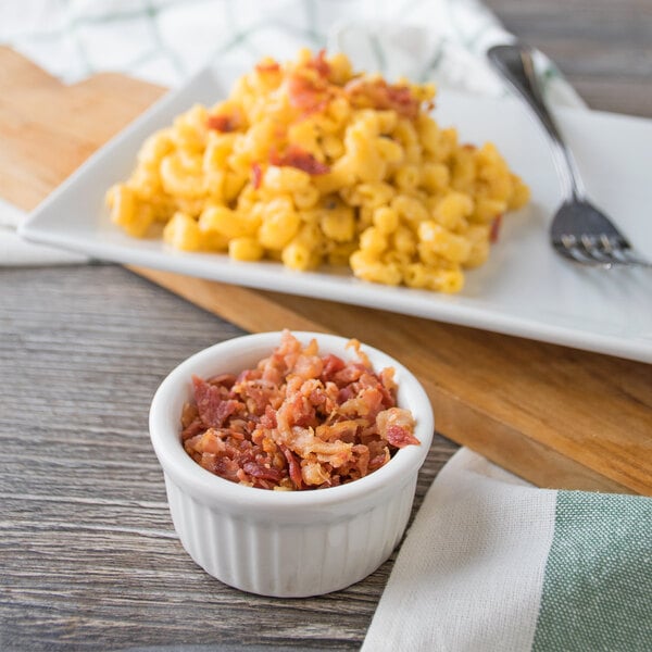 A plate of macaroni and cheese topped with diced bacon.