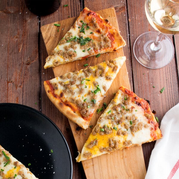 Slices of pizza with pork crumble topping on a wood board with a glass of wine.