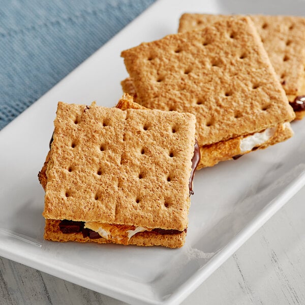 A plate with three s'mores made with Keebler Graham Crackers on a table.