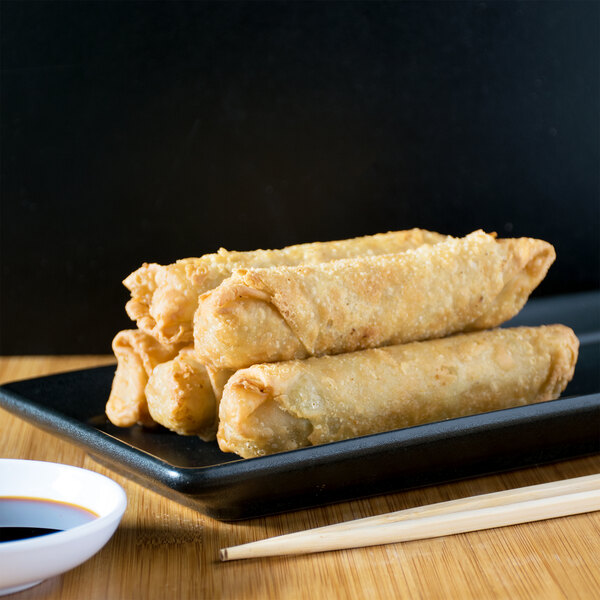 A plate of Minh Pork and Vegetable Egg Rolls on a black plate.