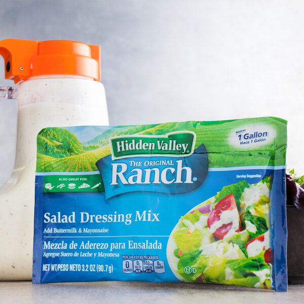A bag of Hidden Valley Ranch salad dressing mix next to a container of salad.
