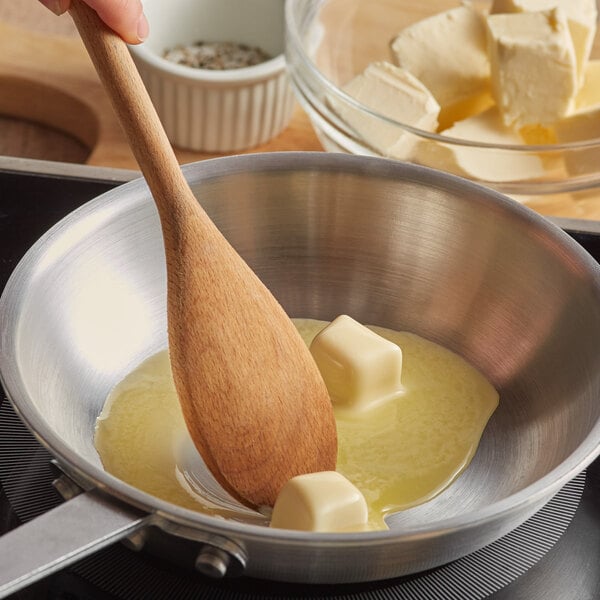 A person stirring Trans Fat Free Buttery Blend in a pan with a wooden spoon.