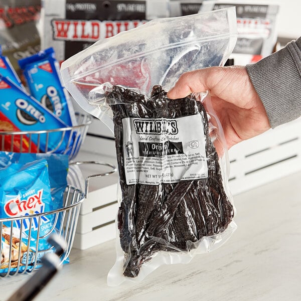 A person holding a package of Wild Bill's hickory-smoked beef jerky.