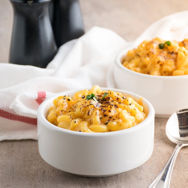 Two bowls of Costa elbow macaroni and cheese on a table with a spoon.