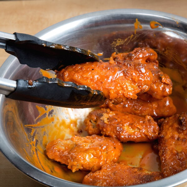 A bowl of chicken wings with Sweet Baby Ray's Buffalo Wing Sauce and tongs.