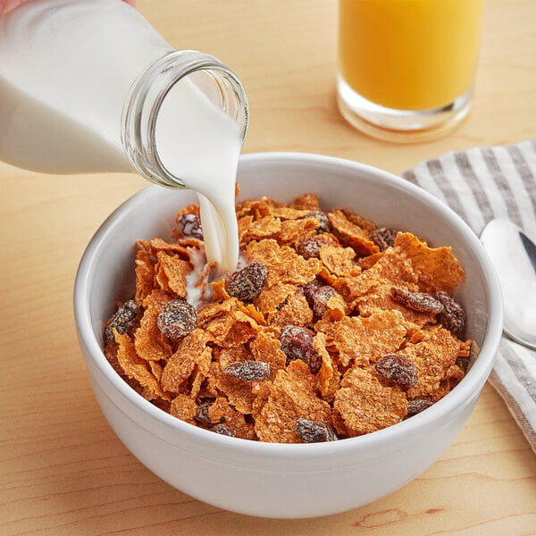 A bowl of Kellogg's Raisin Bran cereal with milk being poured into it.