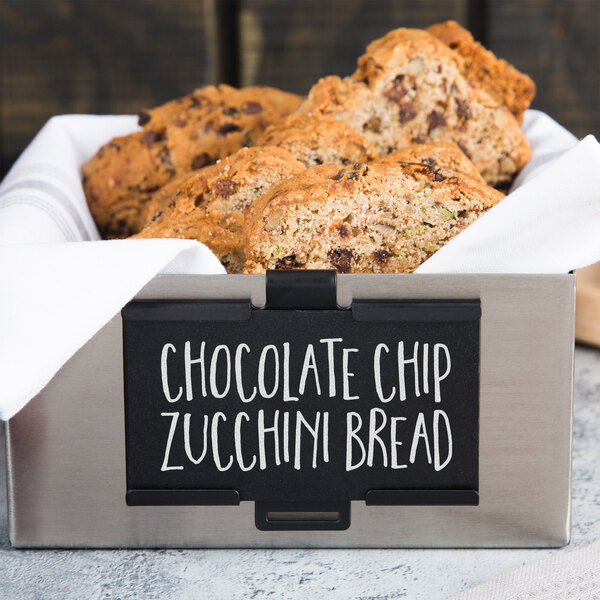 A black metal Tablecraft card holder holding a white sign with chocolate chip zucchini bread.