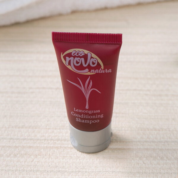 A close-up of a small red bottle of Noble Eco Novo Natura Conditioning Shampoo with white text.