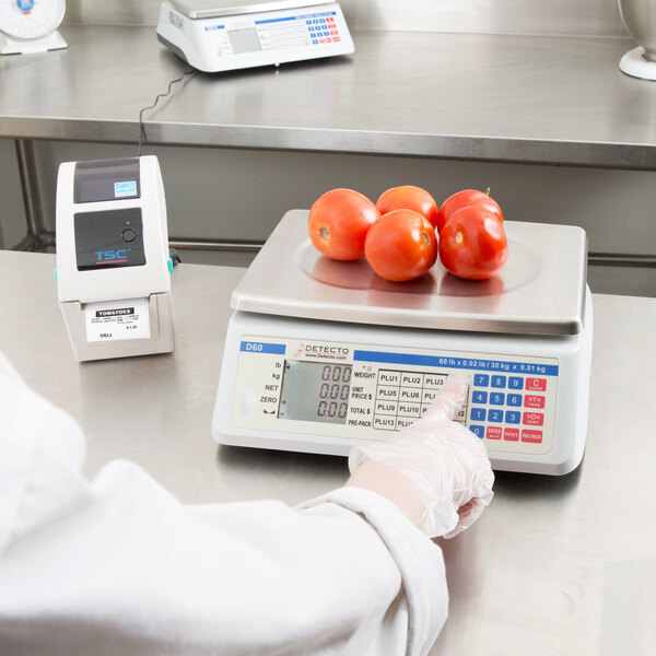 A person using a Cardinal Detecto price computing scale to weigh tomatoes.