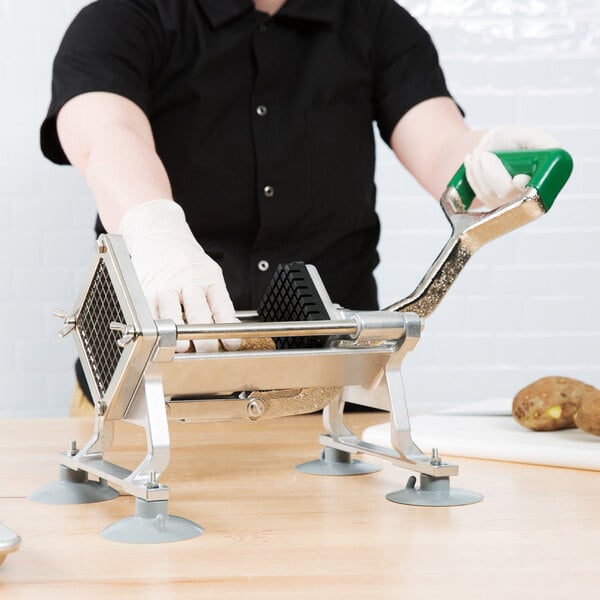 A person using a Garde Heavy-Duty French Fry Cutter to cut potatoes.