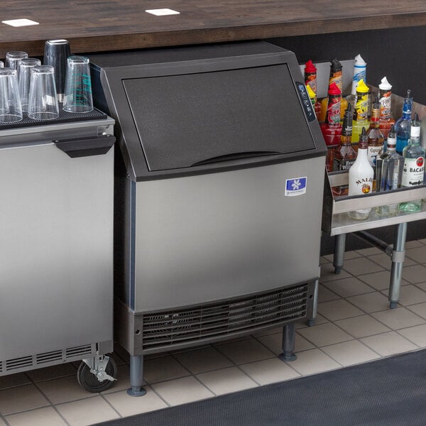 A stainless steel Manitowoc undercounter ice machine with ice inside.