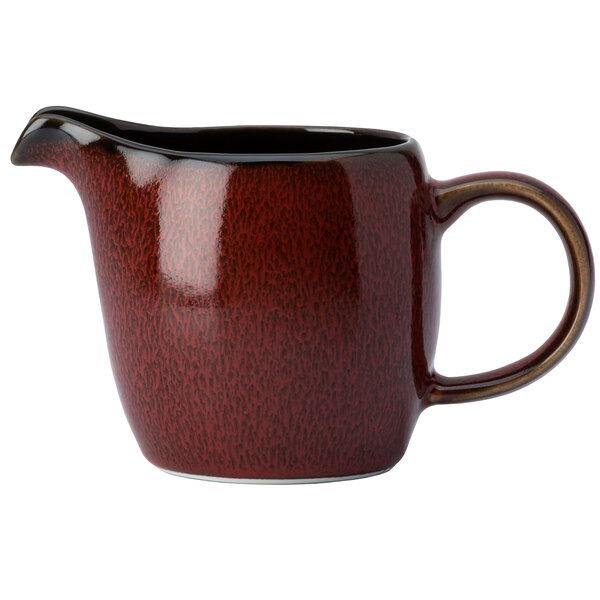 A red and white ceramic creamer with a brown handle.