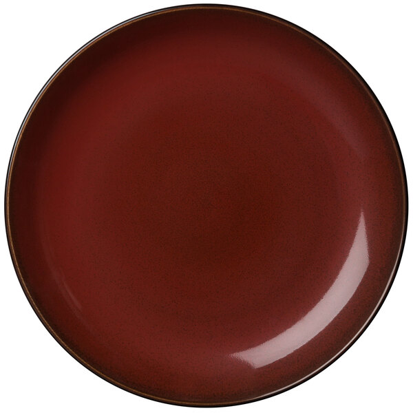 A close-up of a white porcelain round coupe plate with a crimson rim.