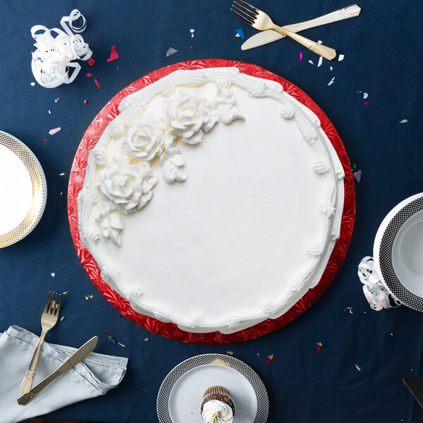 A round red cake on a white and red plate on a blue surface.