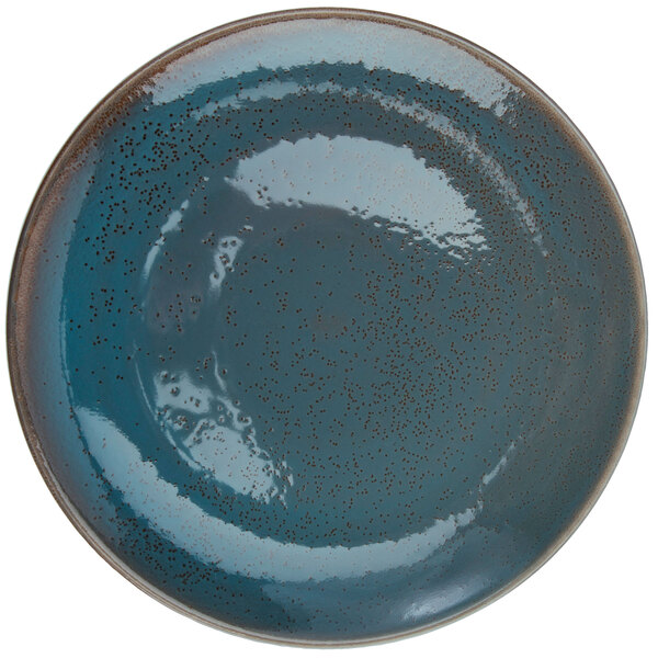 A white porcelain round coupe plate with blue and speckled brown spots.