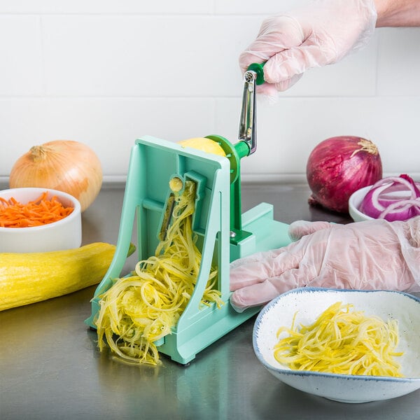 A person using a Benriner manual spiralizer to cut an onion over a bowl of food.