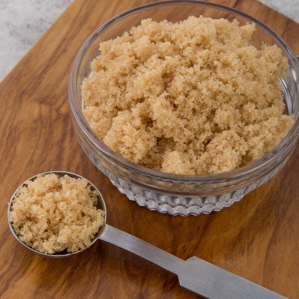 A bowl of Domino light brown sugar with a spoon in it.