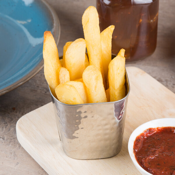 An American Metalcraft stainless steel square fry cup filled with french fries on a table.