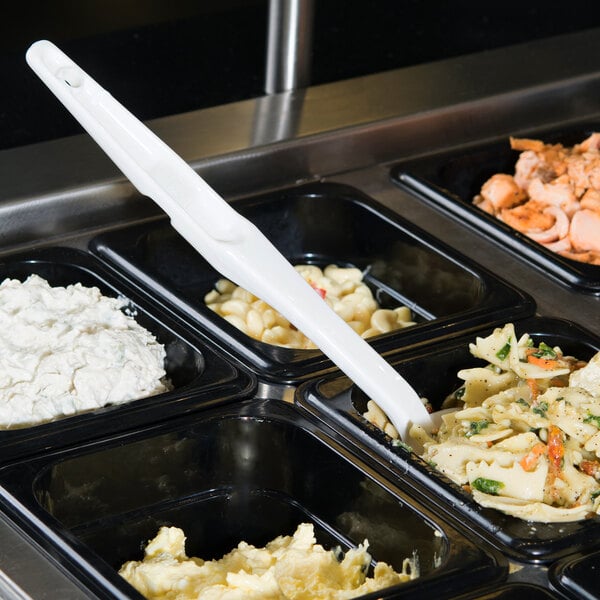 A white Cambro salad bar spoon in a tray of food.