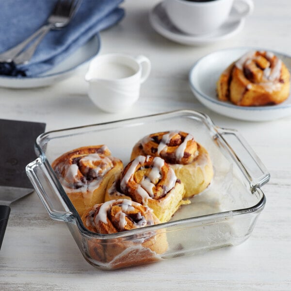 A glass baking dish with cinnamon rolls on a counter.