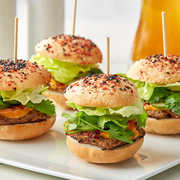 A plate with four mini burgers, each with a Royal Paper round bamboo skewer.
