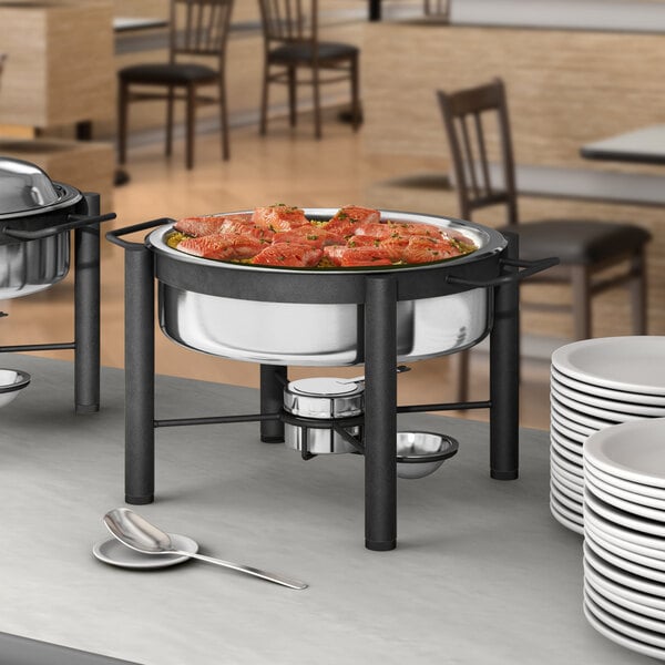 An Acopa wrought iron chafer with food on a table.