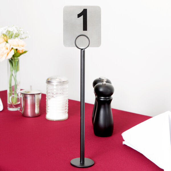 A Tablecraft black flat bottom menu holder with a table number in it.