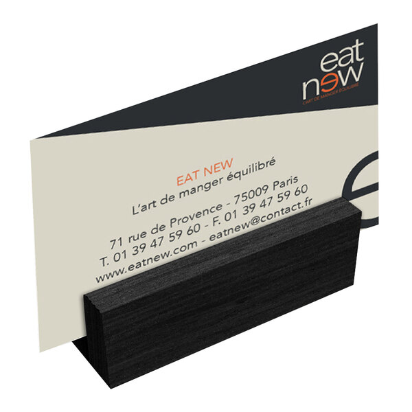 A Menu Solutions black wood mini card holder on a table holding a business card.