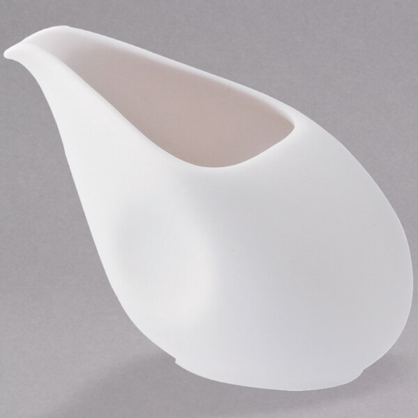 A white ceramic Oneida Stage porcelain creamer with a curved edge.